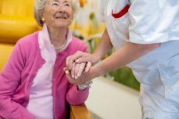 Afbeelding van een arts die een oudere dame een hand geeft