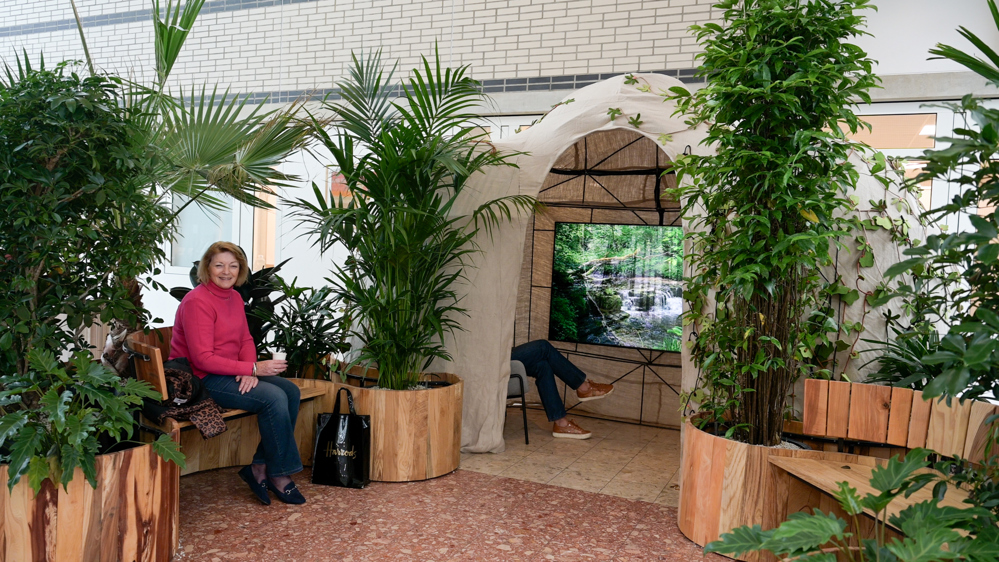 Afbeelding van de groene oase en een vrouw die lachend ernaast zit